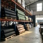 Tumpukan gulungan bahan kain cordura dan kanvas di gudang konveksi
