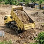 Truk Engkel Plat D Membuang Brangkal untuk Urugan Proyek Jalan